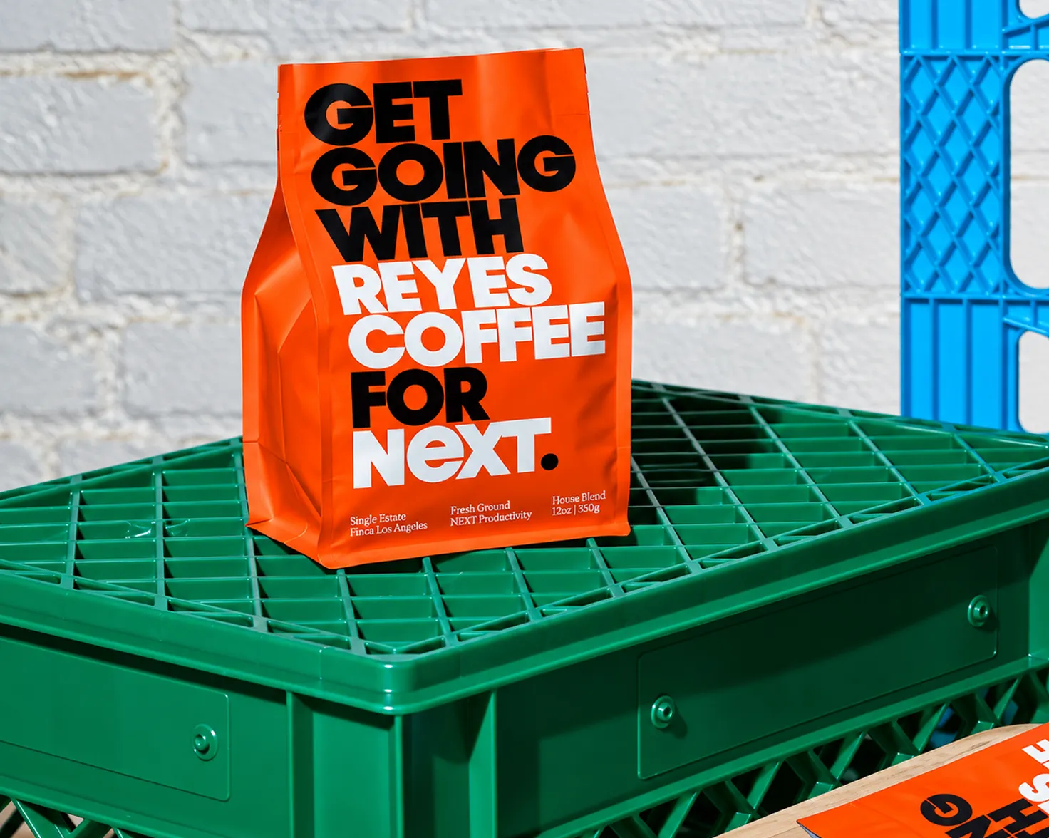 Branded orange coffee pouch standing on a green crate