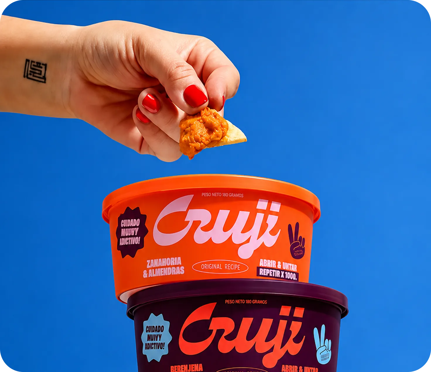 A hand dipping a snack into a branded snack tub