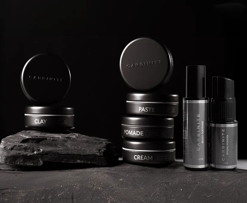 Black grooming tins and bottles on dark stone
