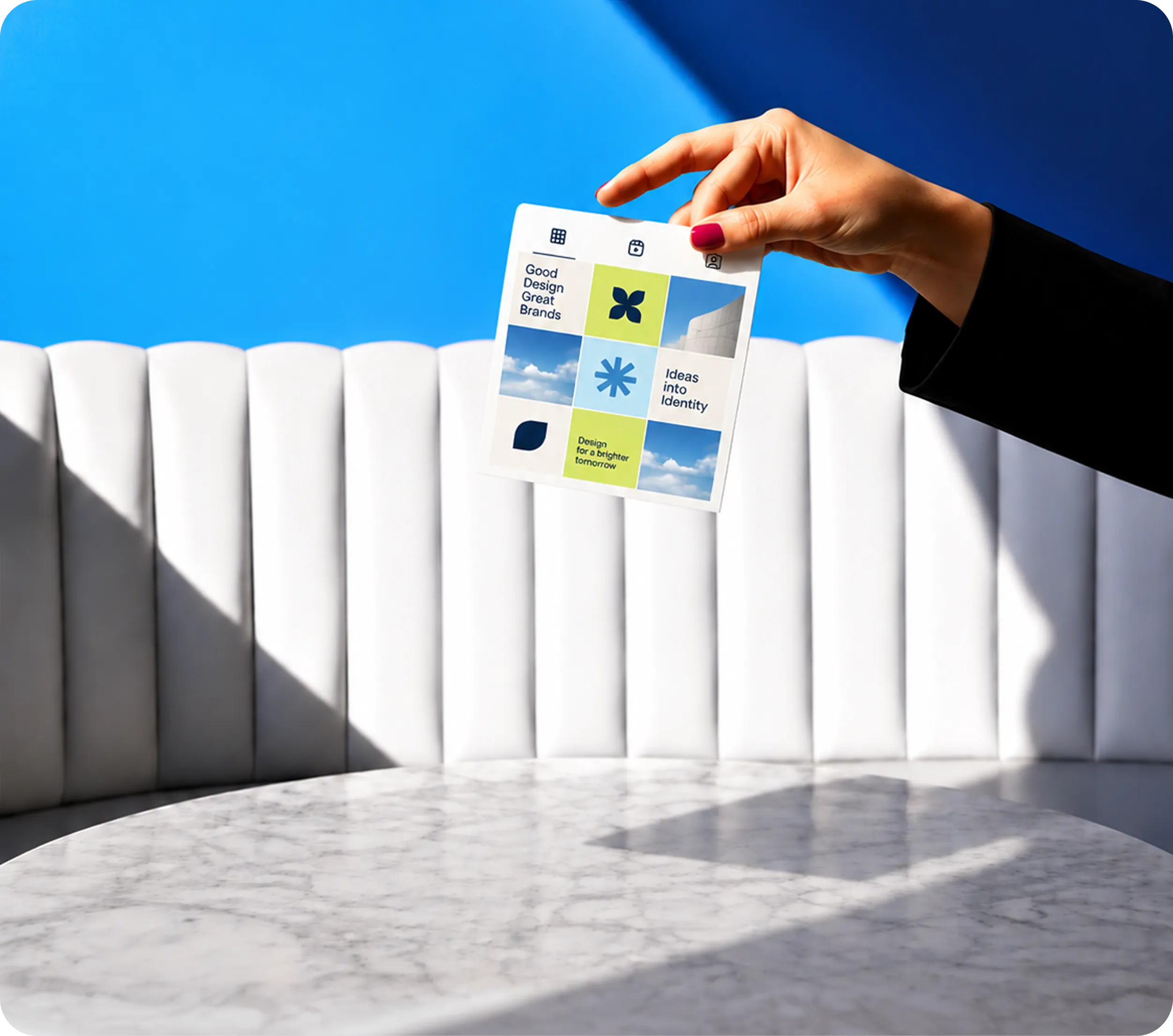 Hand holding a printed grid of branded social media posts